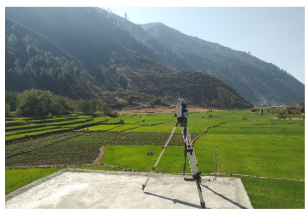 Survey equipment overlooking agricultural fields and hills